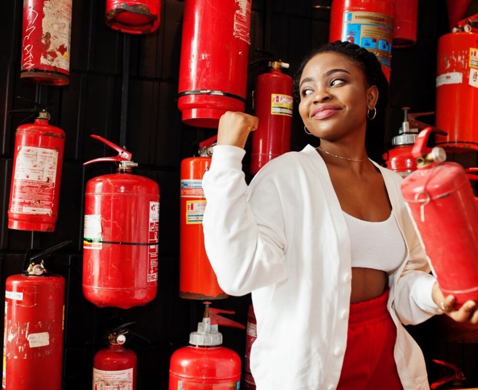 african-woman-posed-against-wall-with-old-extinguisher